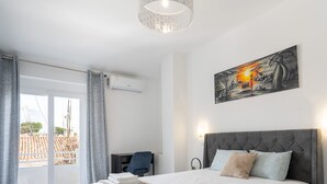 A bedroom with a bed, a desk, and a chair. There is a painting on the wall and a window with curtains. - #268 Marvellous Villa Sapphire by Home Holidays (Albufeira)