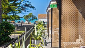 A hotel entrance with a view of the sea, a green exit sign, and a decorative fence. - Orewa Beachcomber  (Orewa)