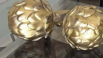 Two golden artichoke sculptures on a glass table.
