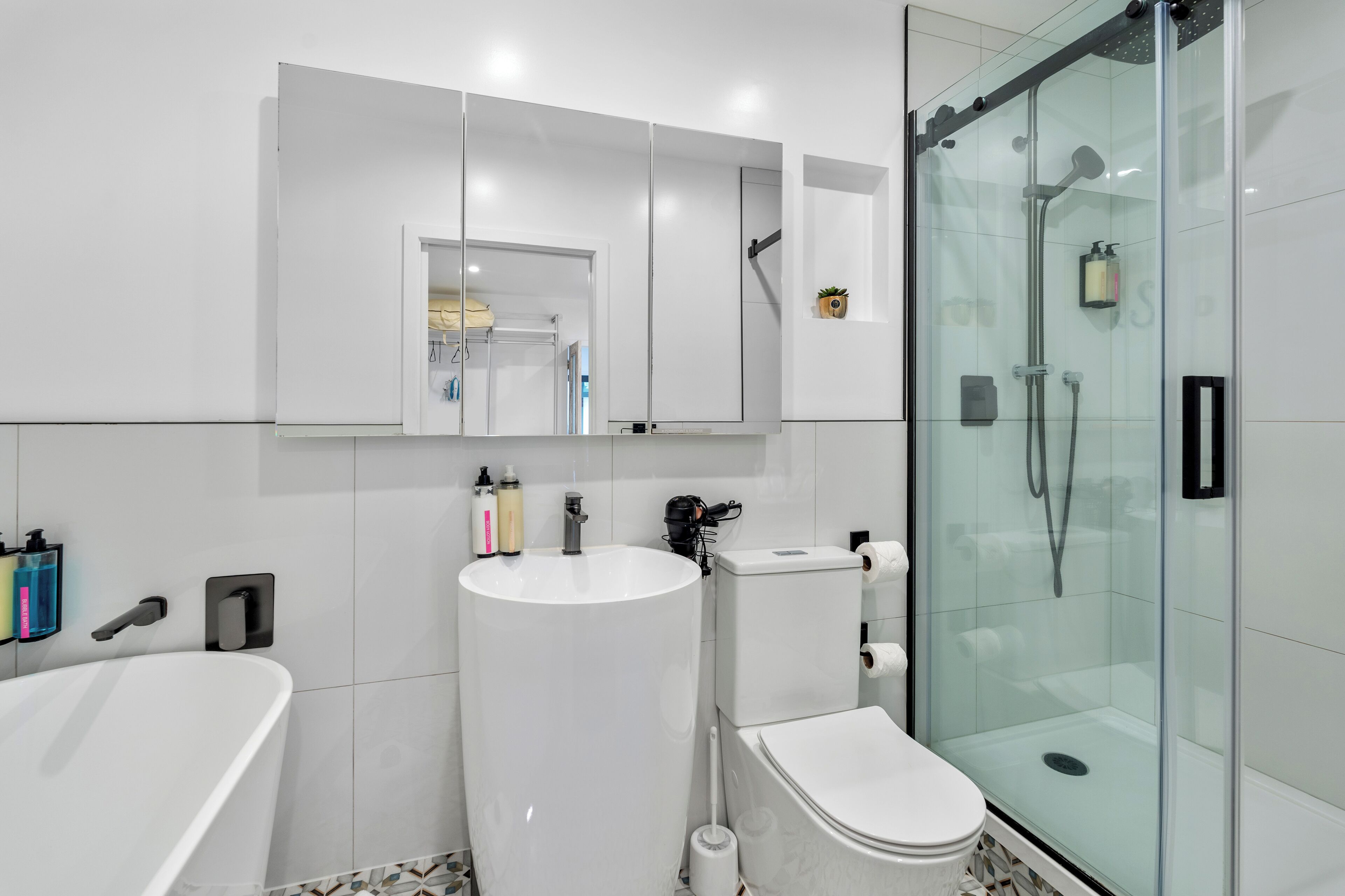 A modern bathroom with a glass-enclosed shower, a freestanding bathtub, and a toilet.