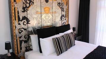 Hotelkamer met een groot bed, zwart-wit gestreepte kussens en een decoratief hoofdbord met een gouden ontwerp.