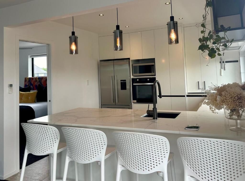 A modern kitchen with a central island, stainless steel appliances, and pendant lighting.