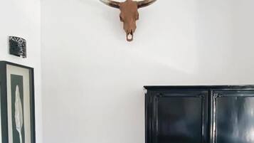Quarto com um armário preto, um quadro na parede e um crânio de touro fixado no teto.