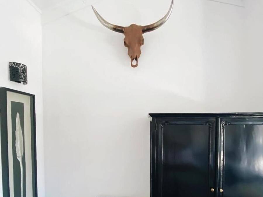 Quarto com um armário preto, um quadro na parede e um crânio de touro fixado no teto.