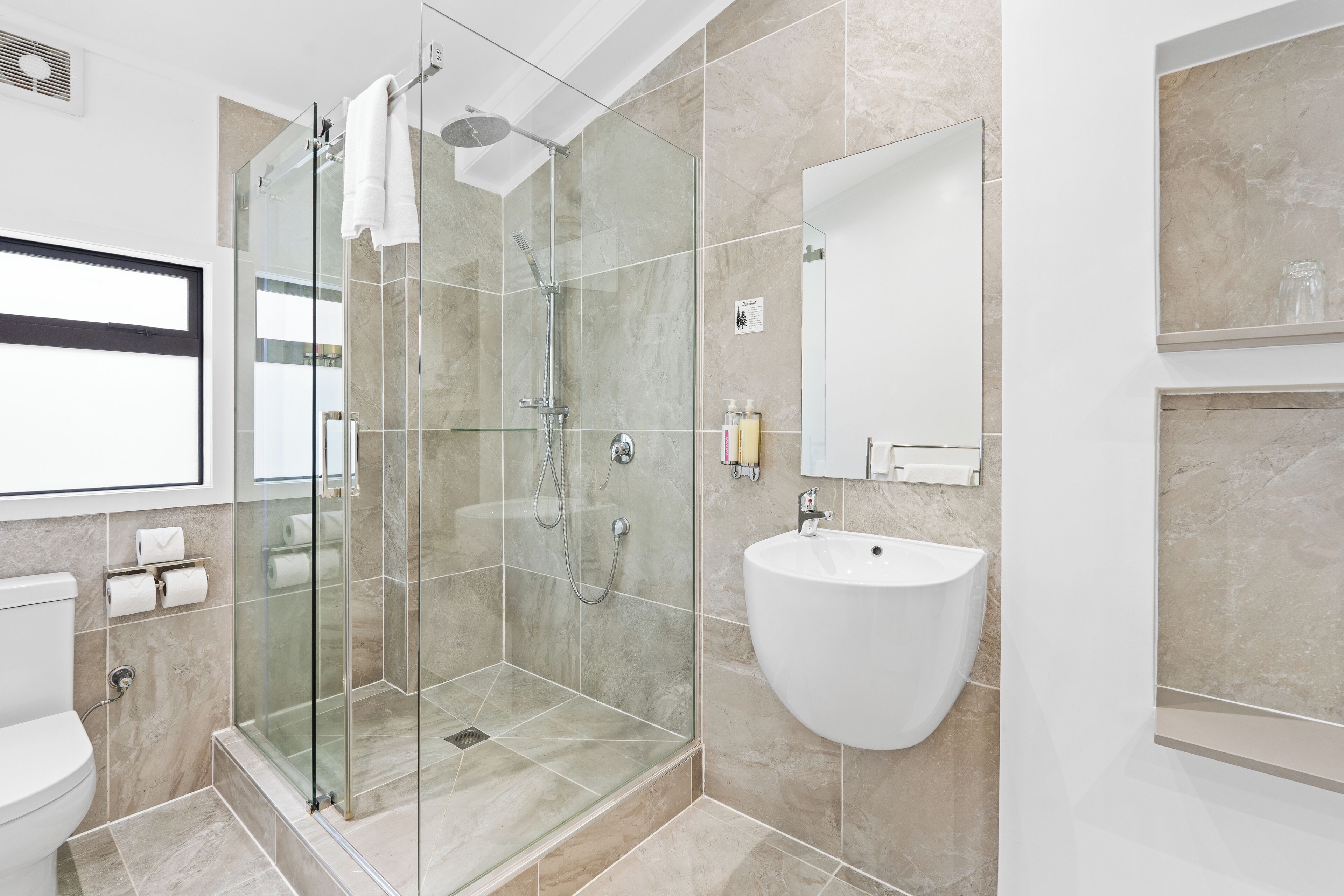 Un bagno moderno con cabina doccia in vetro, un lavandino bianco e un water.