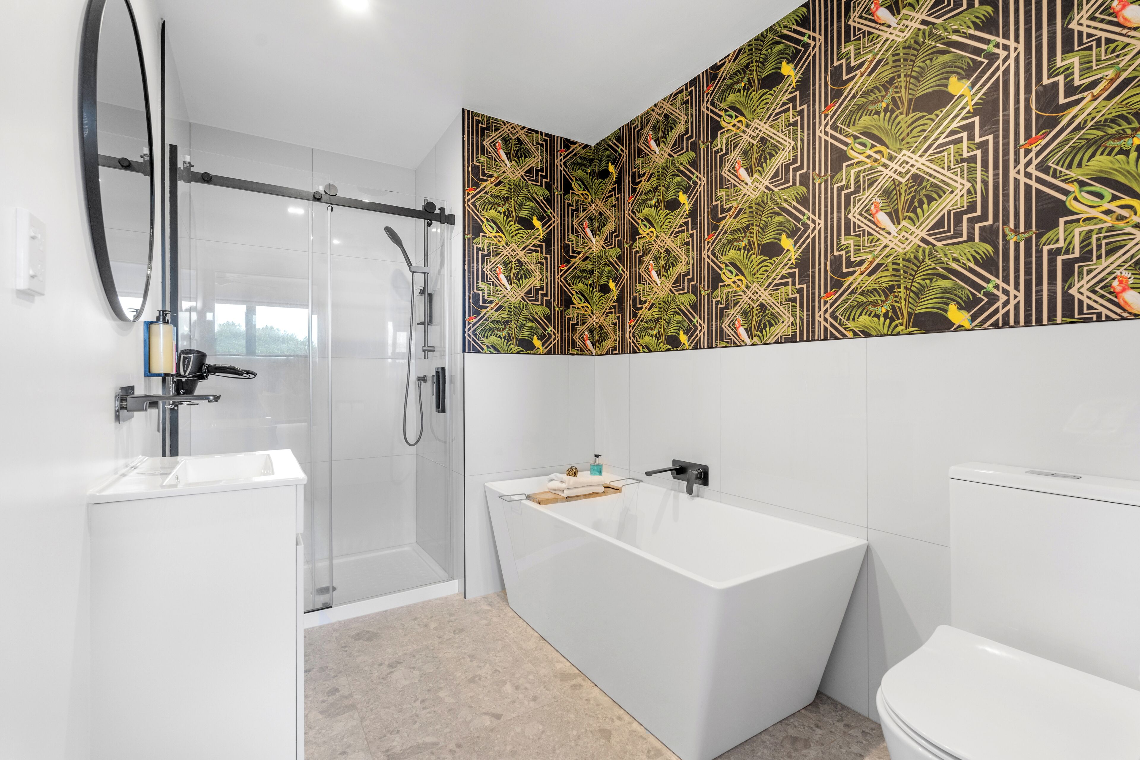Un baño moderno con cabina de ducha de vidrio, una bañera independiente y un inodoro.
