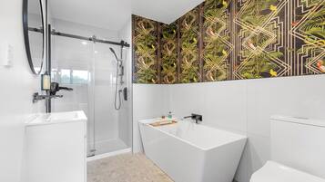 Un baño moderno con cabina de ducha de vidrio, una bañera independiente y un inodoro.