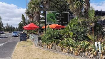 A sign for OREWA BEACHCOMBER with a logo, surrounded by tropical plants and red umbrellas.