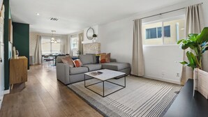 A modern living room with a grey sofa, a coffee table, and a dining area in the background. - Charming Condo in the Pico-Robertson area of LA/2-bed + 2.5 Bath/2 Parking spots (Los Angeles)