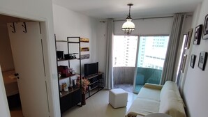 A modern living room with a sofa, a TV, a coffee machine, and a bookshelf. - APARTAMENTO ACONCHEGANTE LIBERDADE SP (São Paulo)