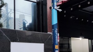 A sign for 'GINZA CONDOMINIO EDIFICIO GINZA 700' with a blue pillar and a potted plant nearby. - APARTAMENTO ACONCHEGANTE LIBERDADE SP (São Paulo)