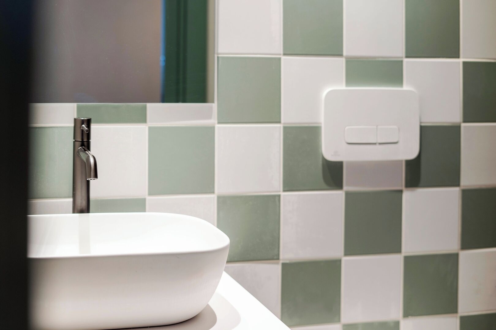 A bathroom with a white sink and a modern faucet.