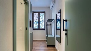 A hallway with a wooden floor, a window with a geometric pattern, and a mirror on the wall. - VLC HOST - Reina 168 2 (Valencia)