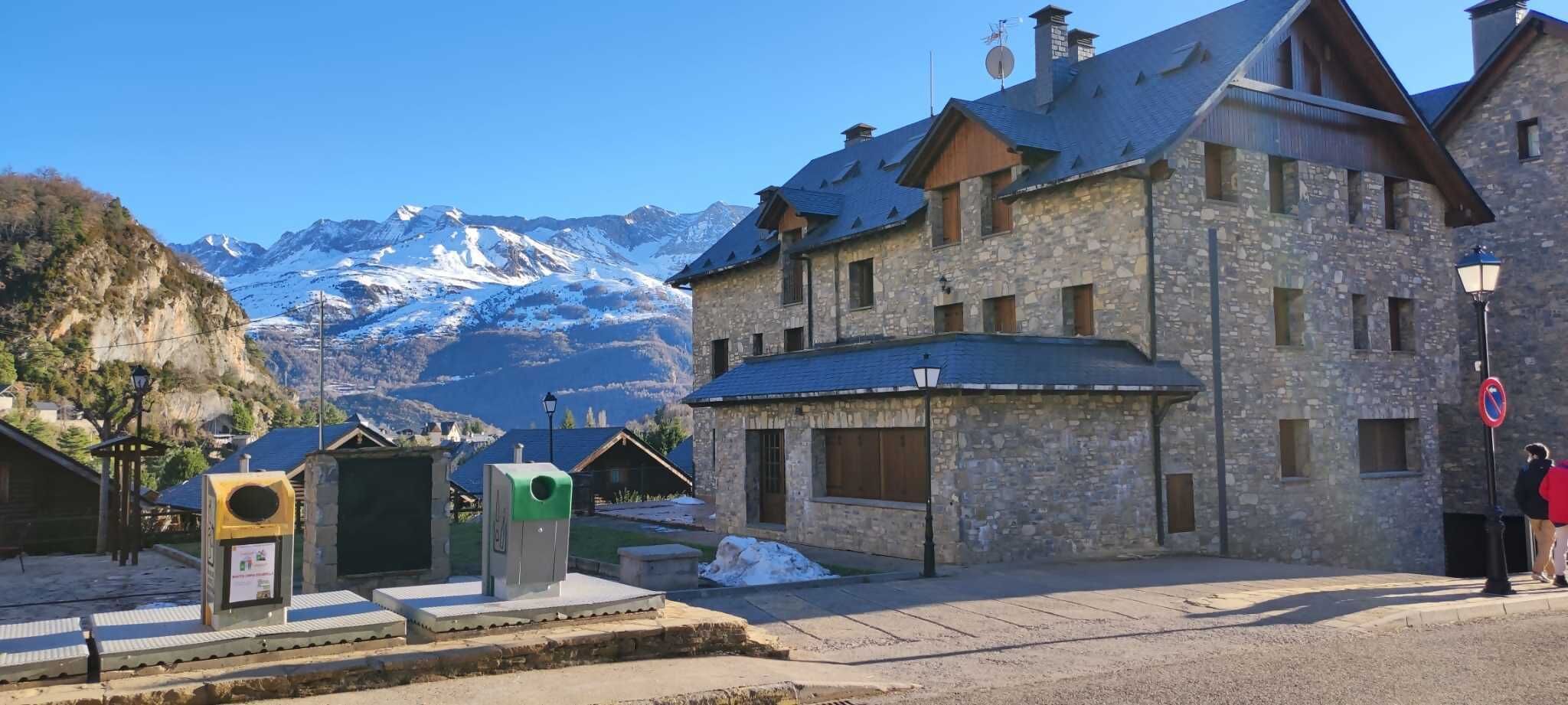 Een gebouw van steen met een schuin dak, een bord met daarop 'niet parkeren' en een uitzicht op besneeuwde bergen op de achtergrond.