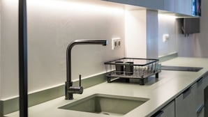 A modern kitchen with a single sink, a black faucet, and a small black kitchen island with two black containers. - VLC HOST - Reina 168 1 (Valencia)