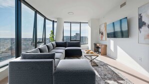 Un salon moderne avec un canapé d’angle, une table basse et un grand téléviseur fixé au mur.