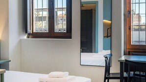 A hotel room with a bed, a desk, a chair, a large mirror, and a window with bars. - VLC HOST - Reina 168 4 (Valencia)