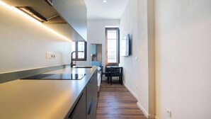 A modern kitchen with a built-in island, a dining area with a table and chairs, and a large window providing natural light. - VLC HOST - Reina 168 4 (Valencia)