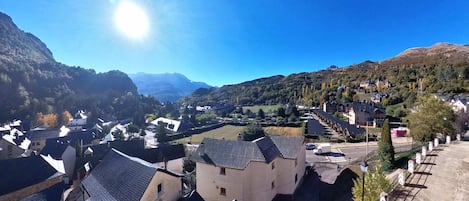 Un village de montagne à l’architecture traditionnelle, avec un ciel dégagé et une vallée.