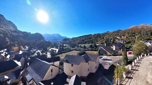 Un pueblo montañoso con arquitectura tradicional, cielo despejado y un valle.