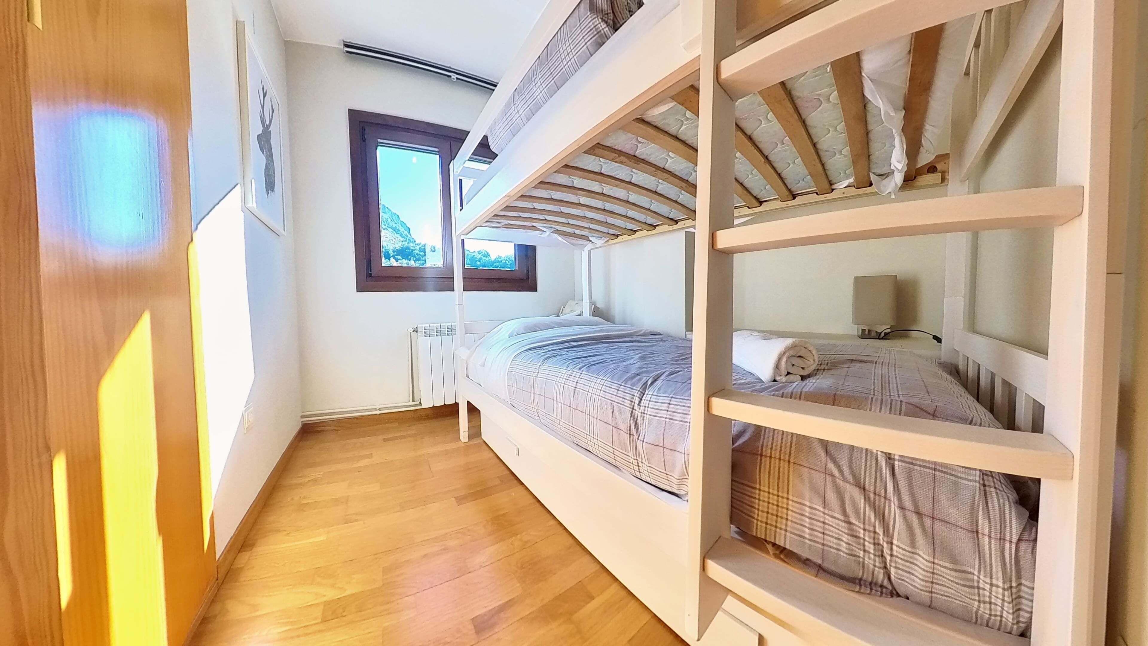 Una habitación con literas, ventana con vistas y un radiador.