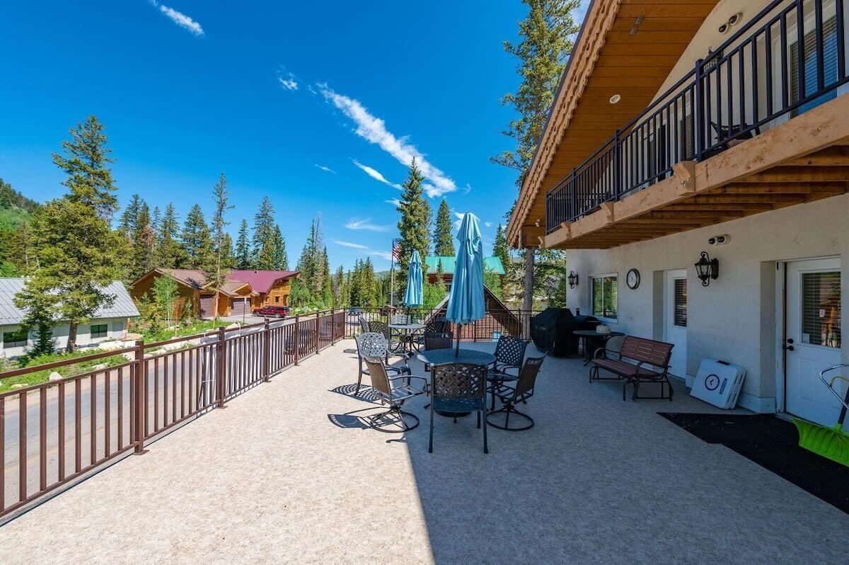 A patio with outdoor seating, a barbecue area, and a view of surrounding trees and buildings.