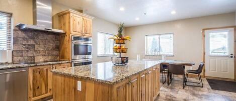 A kitchen with wooden cabinets, a granite countertop, a built-in oven, and a fruit basket.