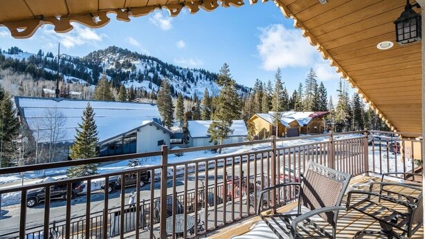 A balcony with a view of a snowy mountain, a wooden ceiling, and outdoor seating. - Brighton Chalet  (Brighton)