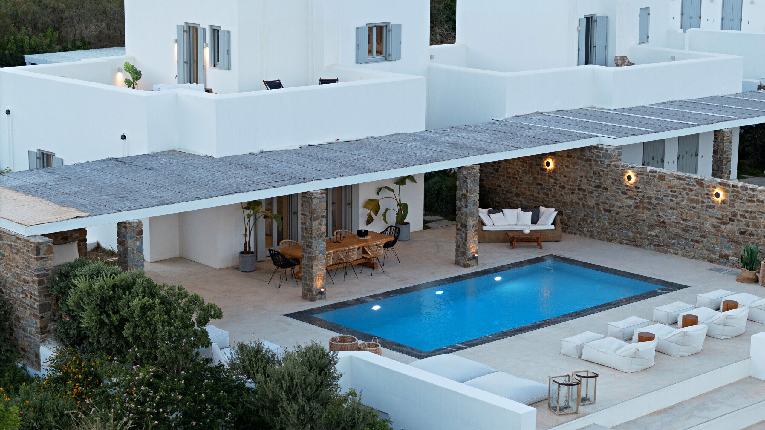 A modern villa with a swimming pool, outdoor seating, and a covered patio area.