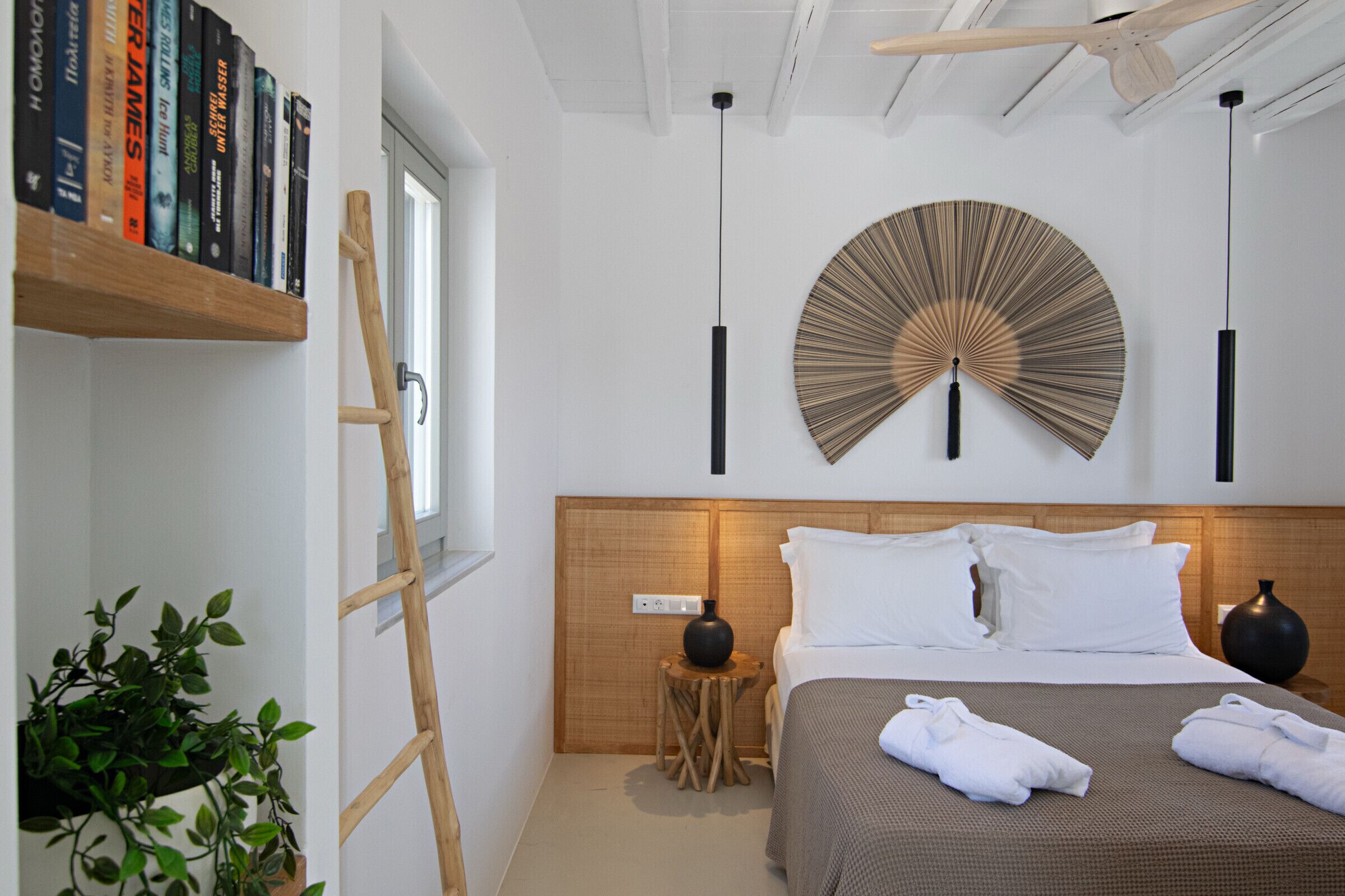 A modern bedroom with a wooden headboard, a round wall decoration, and neatly folded towels on the bed.
