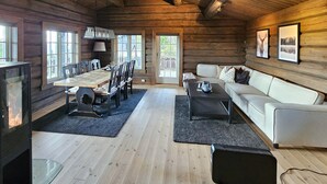 A log cabin interior with a dining table, chairs, a sofa, a fireplace, and framed pictures on the walls. - Amazing home in Nissedal with WiFi (Nissedal)