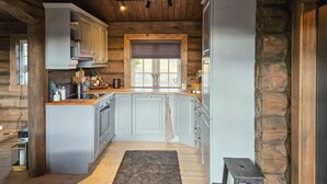 A rustic kitchen with wooden walls, a large island, and a window with a view. - Amazing home in Nissedal with WiFi (Nissedal)