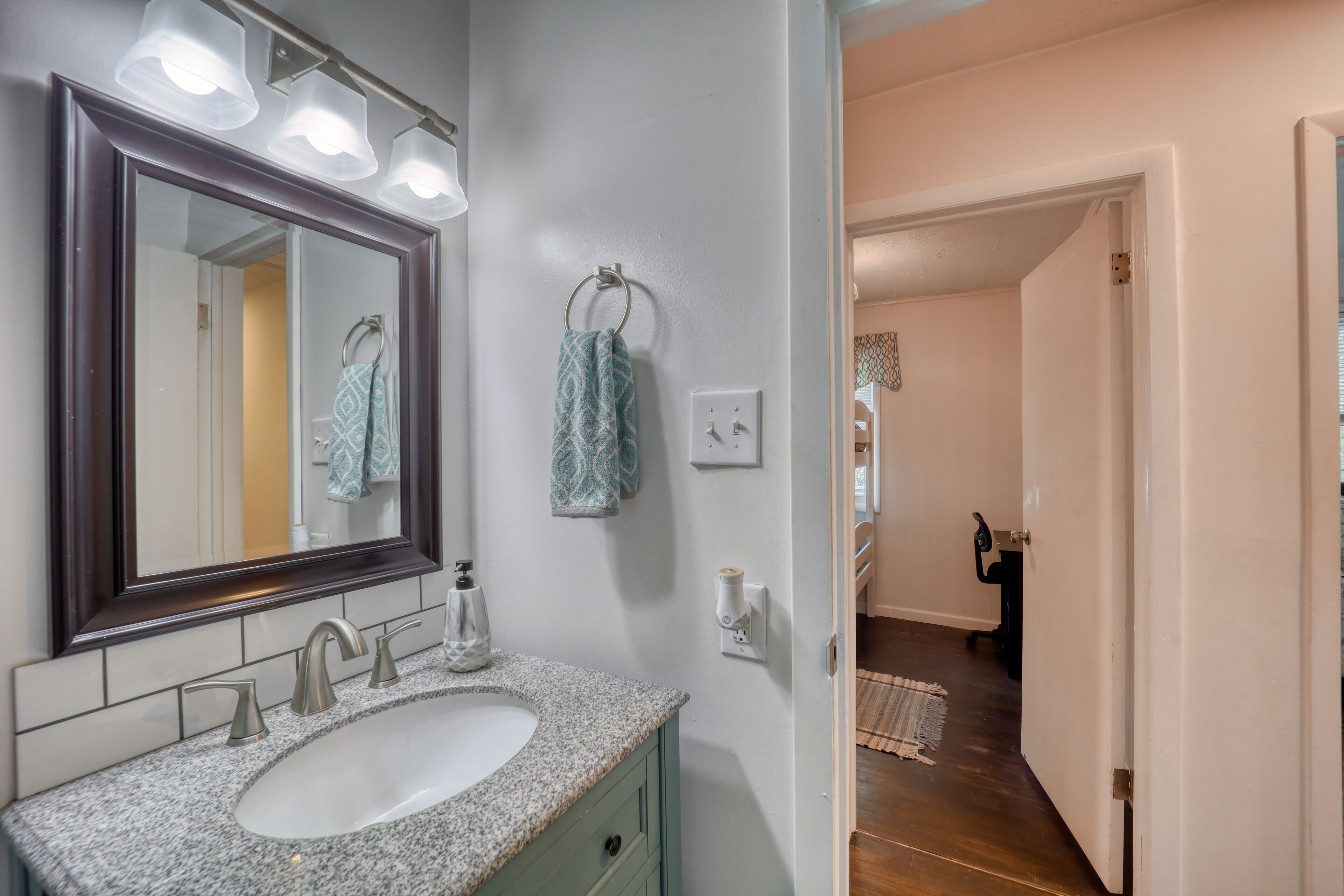 A bathroom with a large mirror, a sink, and a towel rack.