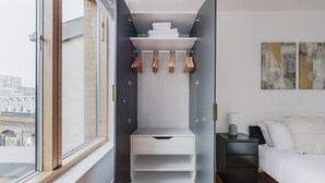 Une chambre à coucher de taille modeste, dotée d’une armoire intégrée, d’une table de chevet et offrant une vue par la fenêtre.