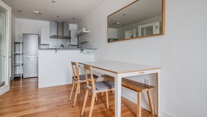Une cuisine moderne avec des meubles blancs, un réfrigérateur en acier inoxydable et une table à manger en bois, assortie de chaises.