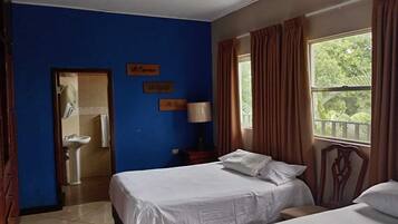 A hotel room with two beds, a bathroom with a sink, and a window with curtains.