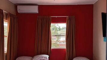 Habitación con dos camas, ventilador de techo, aire acondicionado y ventana con cortinas.