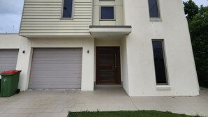 A modern two-story house with a garage, a front door, and a small front yard. - Chevron Island Holiday Home (Surfers Paradise)