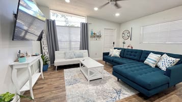 A modern living room with a white sofa, a blue sectional, and a white coffee table.