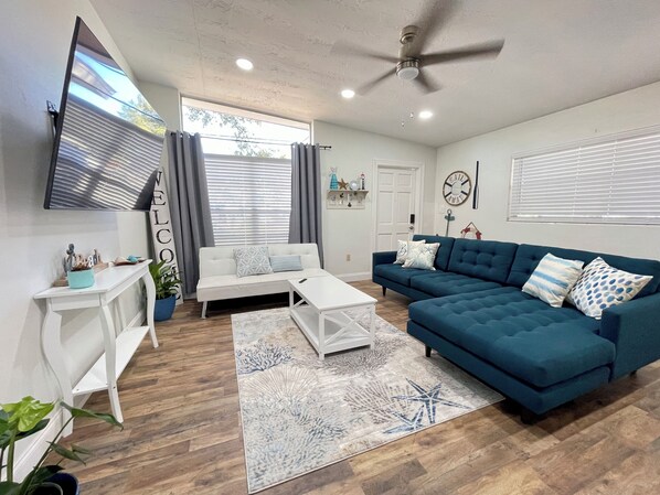 A modern living room with a white sofa, a blue sectional, and a white coffee table.