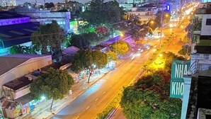 Luchtbeeld van een stadsstraat 's nachts, met verlichte gebouwen, een vrijliggende weg en een bord met de tekst 