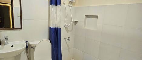 Un baño con inodoro, lavamanos, ducha y un tapete azul en el suelo.