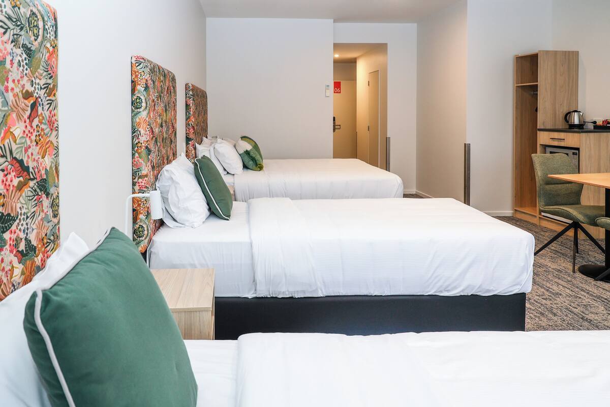 Una habitación de hotel con dos camas, un escritorio, una silla y una kitchenette.