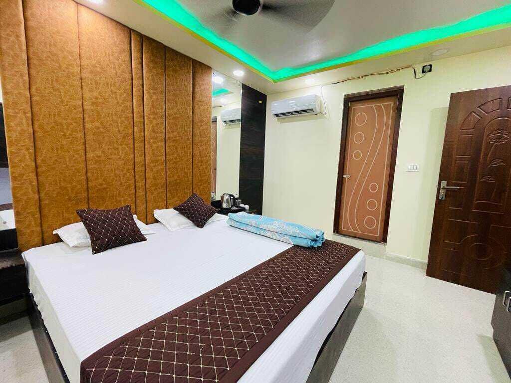 Habitación de hotel con una cama grande, cabecera de madera, ventilador de techo y una puerta con diseño decorativo.