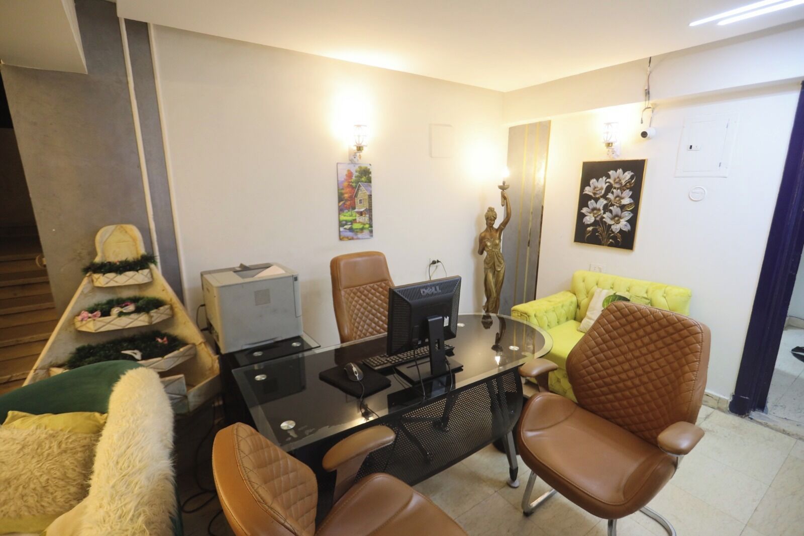 Una sala de estar moderna con una mesa de centro de vidrio, sillones de cuero, un sofá amarillo e impresora.
