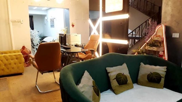 A living room with a green sofa, a yellow armchair, and a brown chair. There is a staircase with a railing and a door leading to another room. - Giza city hotel (Giza)