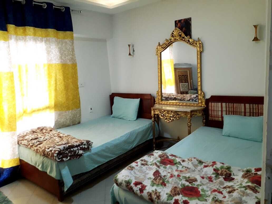 A room with two beds, a large ornate mirror, and a curtain.