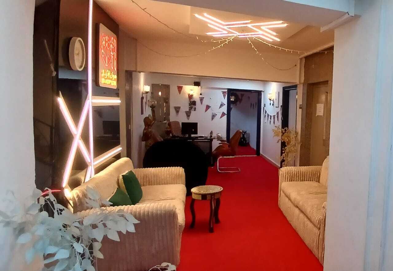 A hotel lobby with a red carpet, two sofas, a small round table, and a decorative wall with string lights.