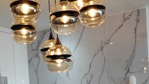 A modern kitchen with a marble backsplash, a black countertop, and a unique hanging light fixture. - Luxury suites polanco  (Ciudad de México)