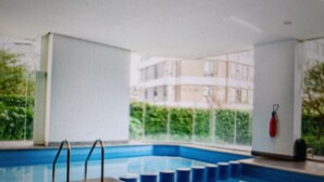 An indoor swimming pool with clear glass walls, a metal ladder, and a red safety buoy. - Luxury suites polanco  (Ciudad de México)
